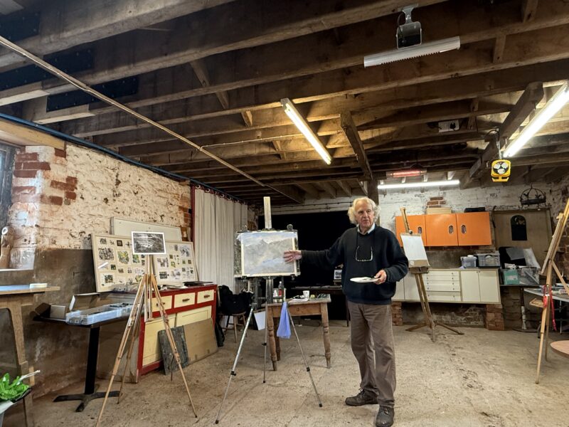 James Tatum teaching painting course in a barn with easels in the background