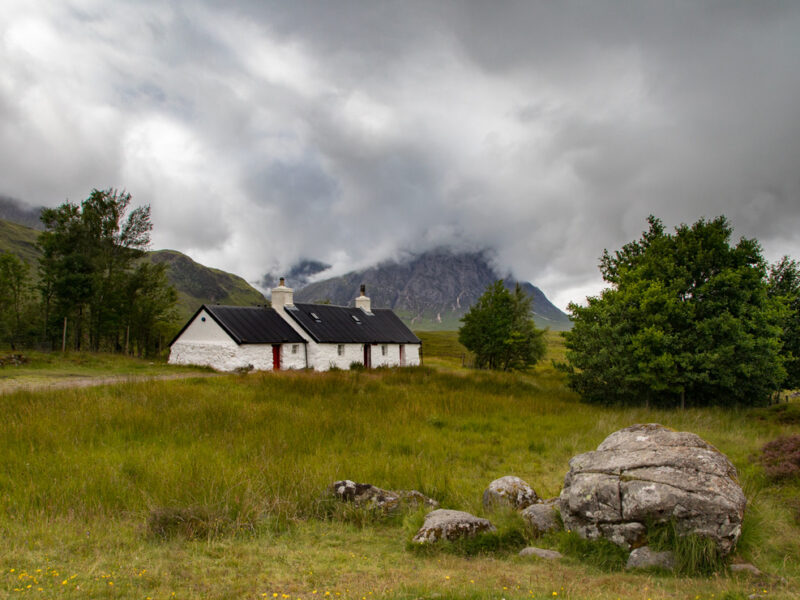 image of a cottage with hills in the distance and a moody grey clouds