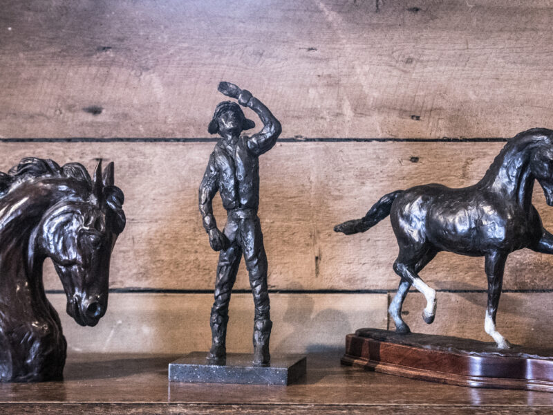 three bronze sculptures, a pilot between two horses